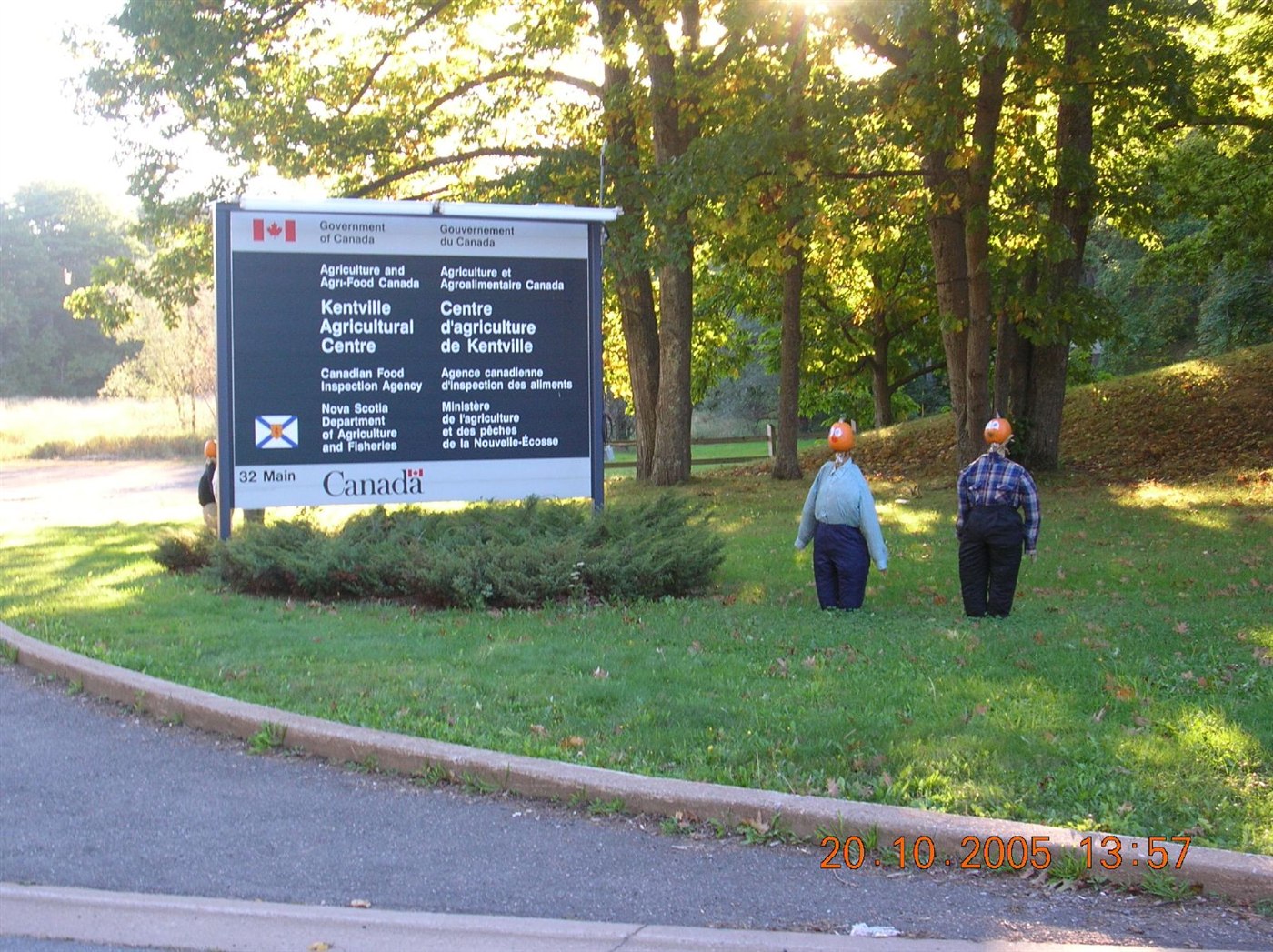 Two pumpkin-headed figures standing beside the Kentville Agricultural Centre sign on Main Street in October 2005.